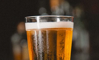 A cold glass of draught lager with a creamy head.
