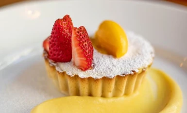 Delicate dessert tart filled with custard and topped with fresh sliced strawberries and peach.