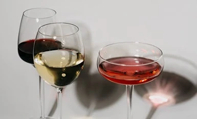 Three elegant wine glasses filled with red, white, and rosé wine against a minimal backdrop.