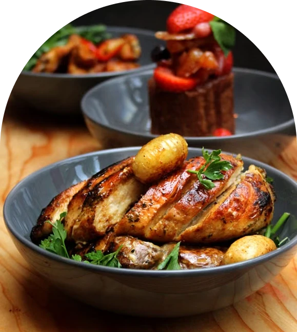 Golden roasted chicken served in a ceramic bowl with baby potatoes and fresh herbs.